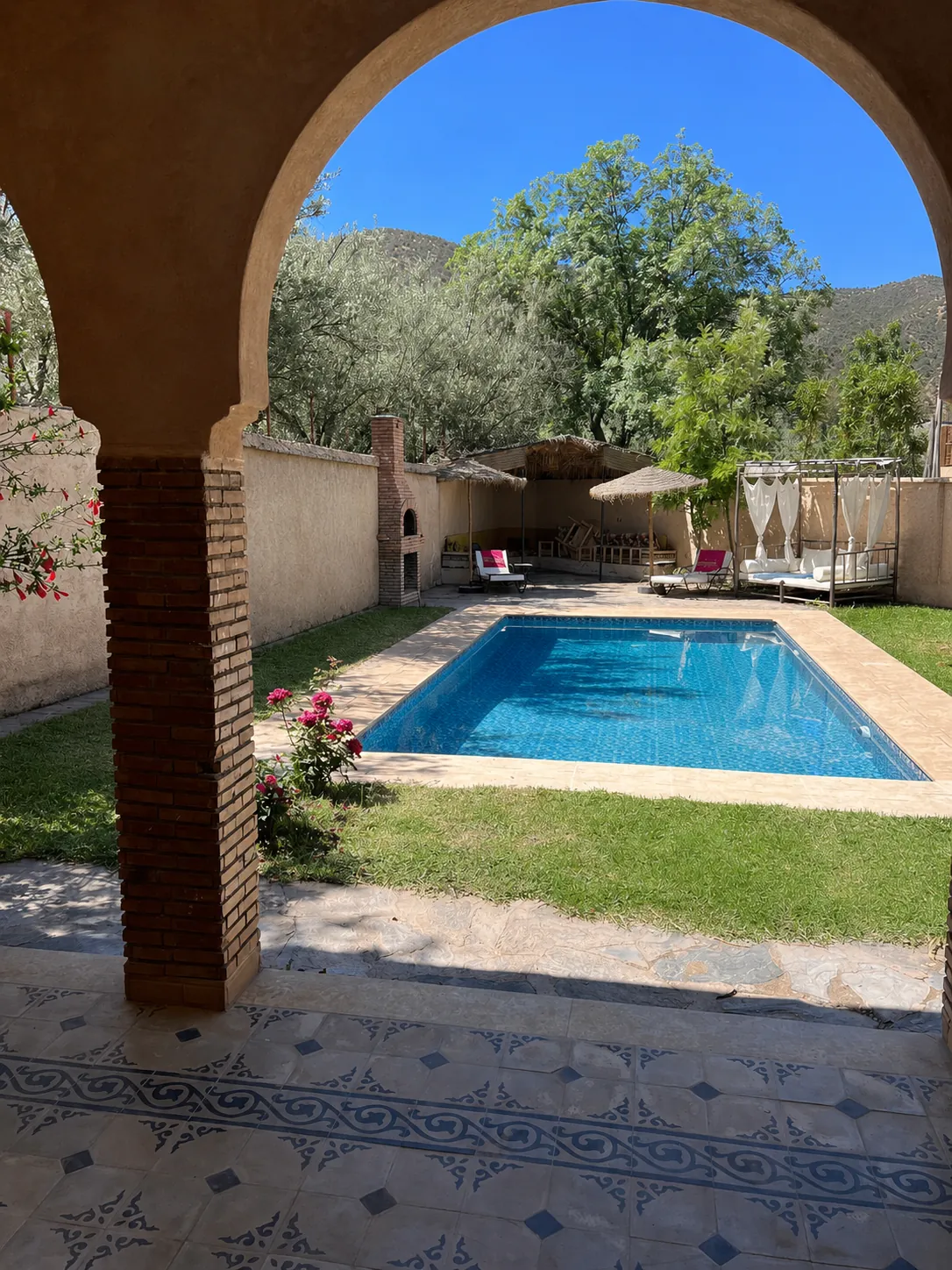 Piscine du lodge Wild Valley Ouirgane vue à travers une arche marocaine traditionnelle